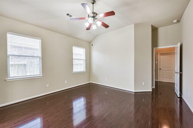 spare room featuring visible vents, baseboards, ceiling fan, vaulted ceiling, and dark wood-style flooring