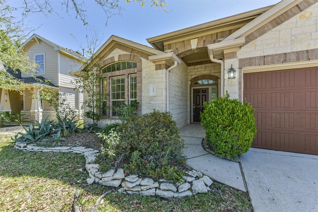 view of exterior entry with stone siding and an attached garage