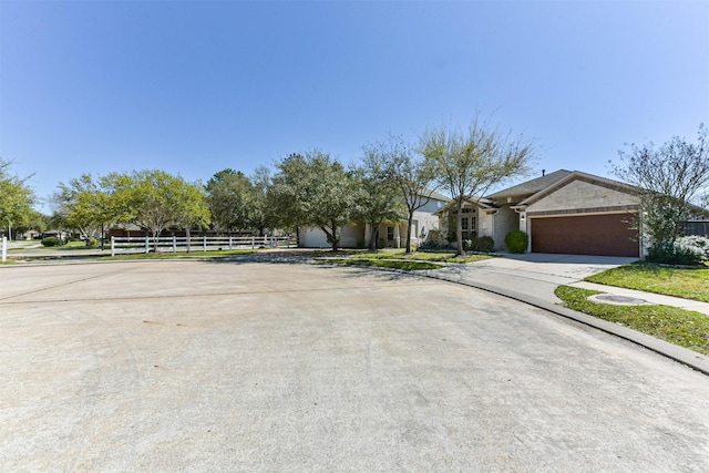 view of front facade featuring concrete driveway, an attached garage, and fence