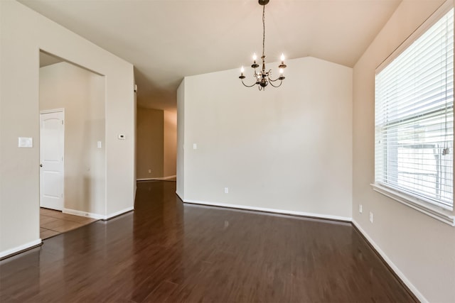 empty room with baseboards, an inviting chandelier, wood finished floors, and vaulted ceiling