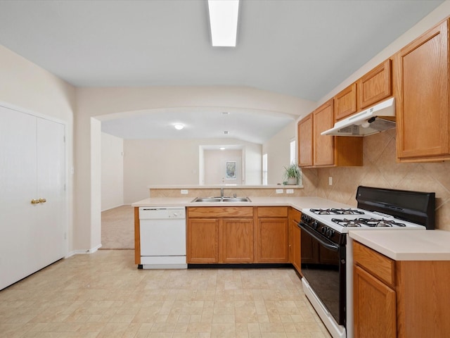 kitchen featuring under cabinet range hood, a sink, a peninsula, white dishwasher, and gas range