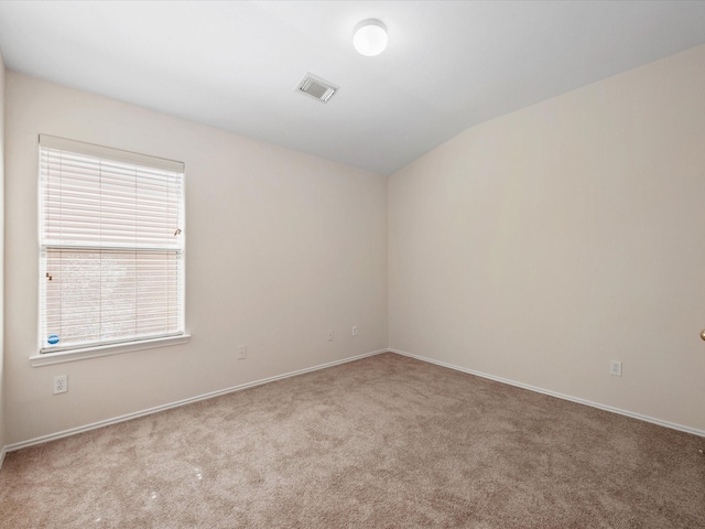 spare room featuring visible vents, carpet flooring, and vaulted ceiling