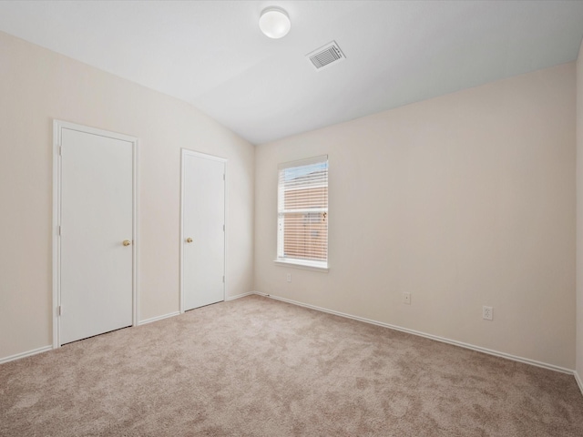 unfurnished bedroom featuring visible vents, lofted ceiling, and carpet