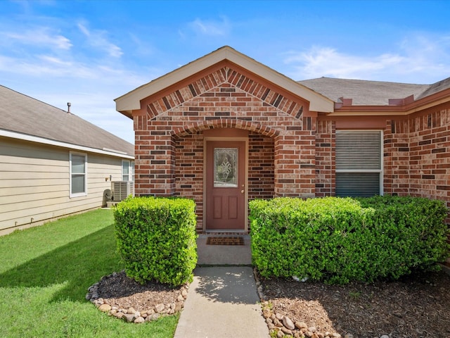 doorway to property featuring a lawn and brick siding