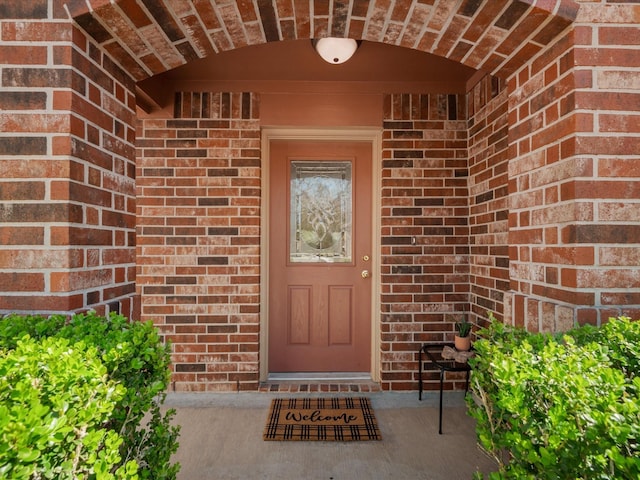 view of exterior entry featuring brick siding