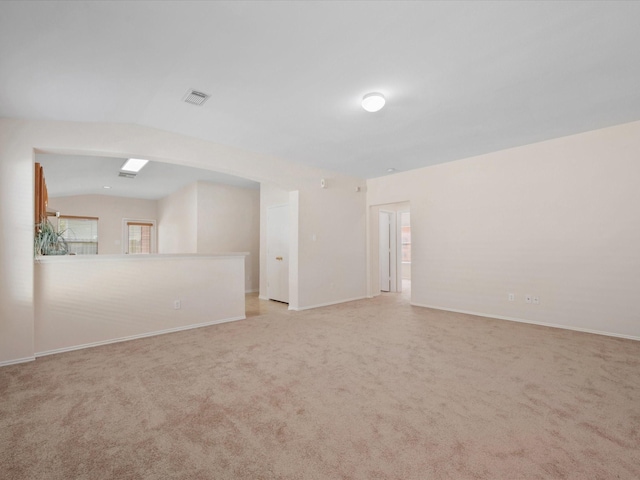 empty room featuring light carpet, visible vents, baseboards, and lofted ceiling