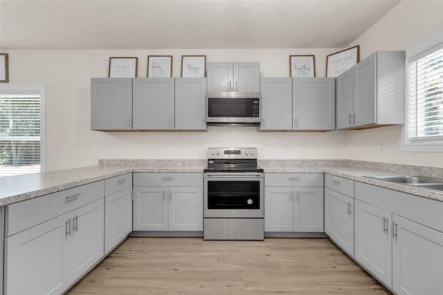 kitchen with a sink, light countertops, light wood finished floors, and stainless steel appliances