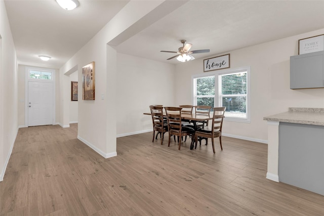 dining area featuring light wood-style flooring, baseboards, and ceiling fan