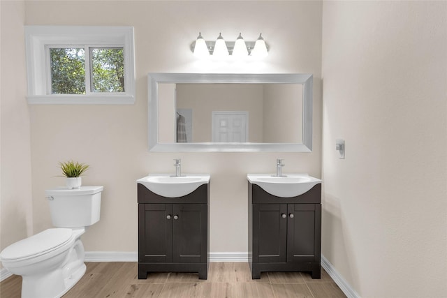 bathroom featuring two vanities, baseboards, and a sink