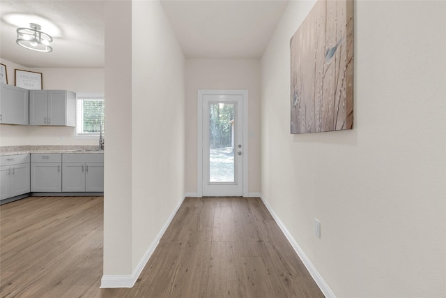 doorway to outside with light wood-type flooring and baseboards