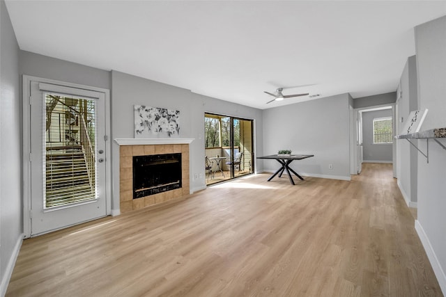 unfurnished living room with light wood-type flooring, baseboards, and a tile fireplace