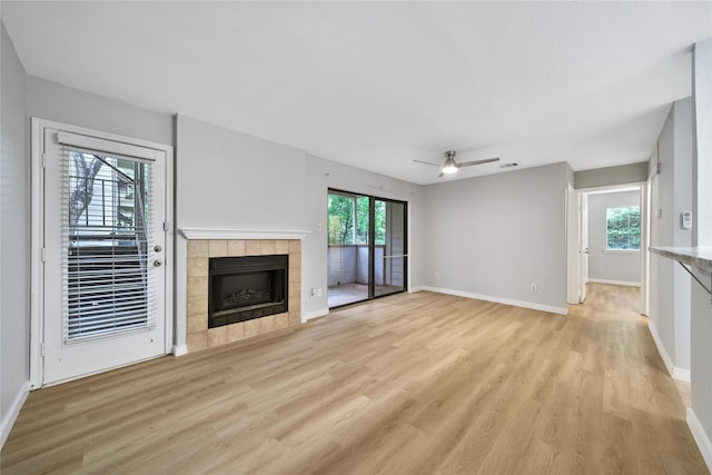 3500 Tangle Brush Dr Unit 142, Spring, TX 77381 - unfurnished living room featuring light wood finished floors, a tiled fireplace, baseboards, and ceiling fan