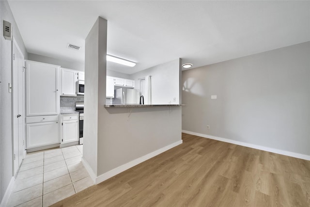 3500 Tangle Brush Dr Unit 142, Spring, TX 77381 - kitchen featuring stainless steel appliances, white cabinets, a breakfast bar, baseboards, and light wood finished floors