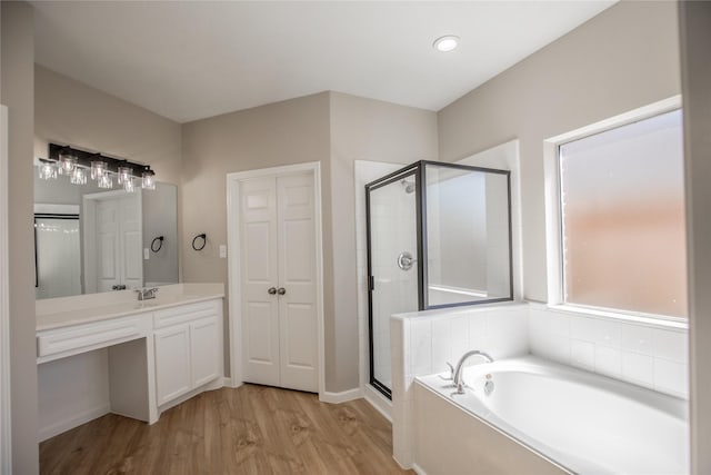 bathroom featuring baseboards, a stall shower, wood finished floors, a bath, and vanity