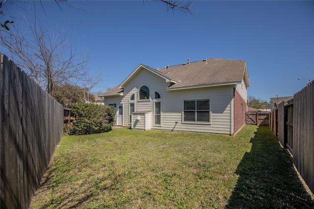 rear view of property featuring a fenced backyard, a yard, and roof with shingles