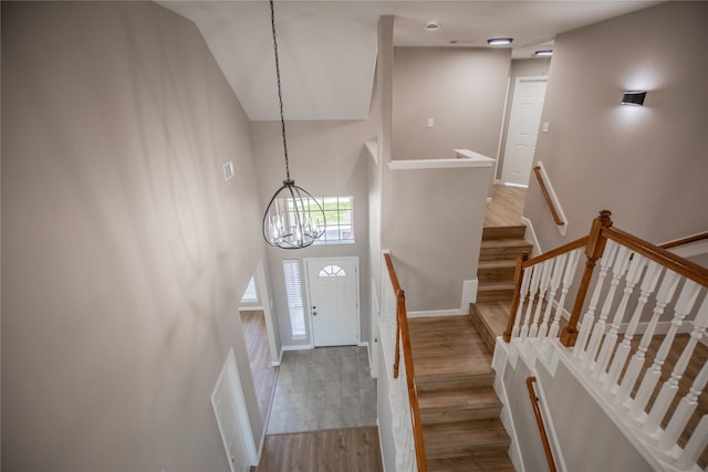 entryway featuring wood finished floors, visible vents, baseboards, a high ceiling, and a chandelier