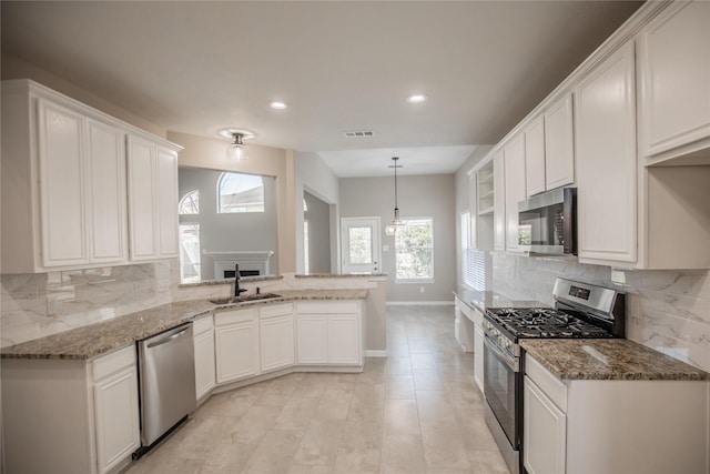 kitchen featuring visible vents, a peninsula, white cabinets, stainless steel appliances, and a sink