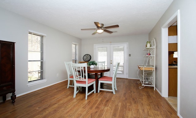 dining room with a ceiling fan, baseboards, light wood finished floors, french doors, and a textured ceiling