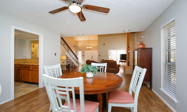 dining room featuring visible vents, a textured ceiling, stairs, and light wood finished floors