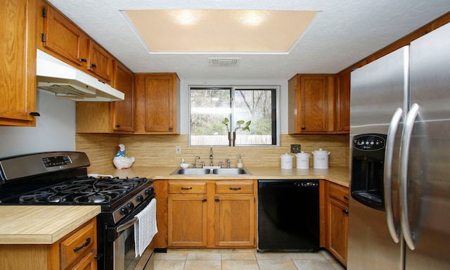 kitchen with visible vents, a sink, light countertops, under cabinet range hood, and appliances with stainless steel finishes