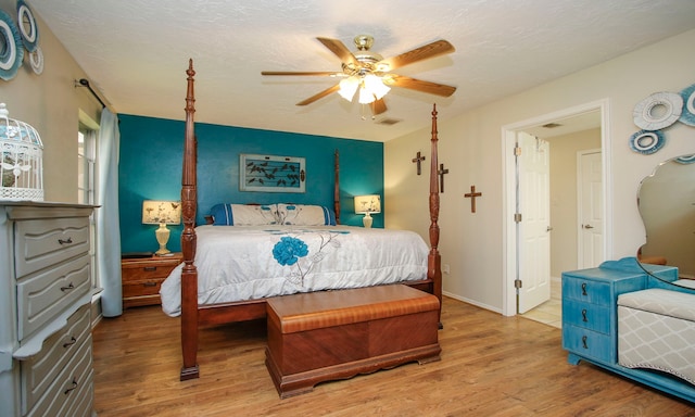 bedroom featuring a textured ceiling, wood finished floors, visible vents, and ceiling fan