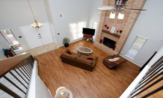 living area with a brick fireplace, stairs, a high ceiling, and wood finished floors