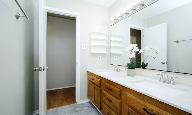 bathroom with a sink, baseboards, and double vanity