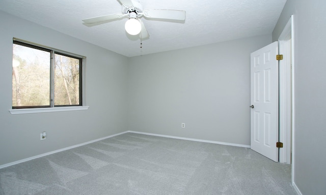 empty room featuring a ceiling fan, baseboards, carpet floors, and a textured ceiling