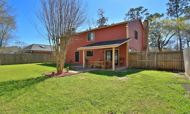 rear view of house featuring a yard, a fenced backyard, a chimney, and a patio area