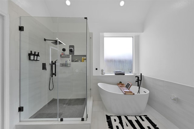 bathroom featuring a soaking tub, a shower stall, and tile walls