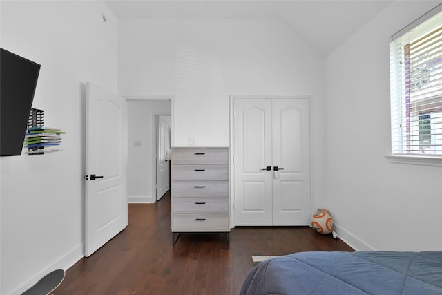 bedroom with a closet, dark wood-type flooring, baseboards, and vaulted ceiling