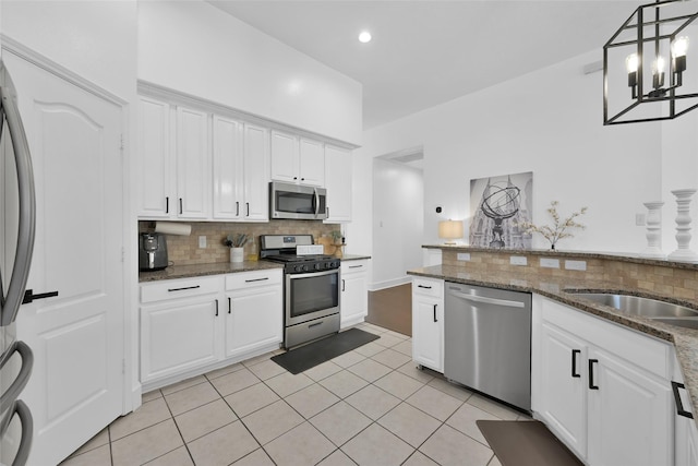 kitchen with light tile patterned floors, stainless steel appliances, backsplash, and white cabinets