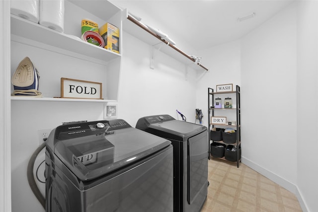 clothes washing area featuring baseboards, light floors, washing machine and dryer, and laundry area