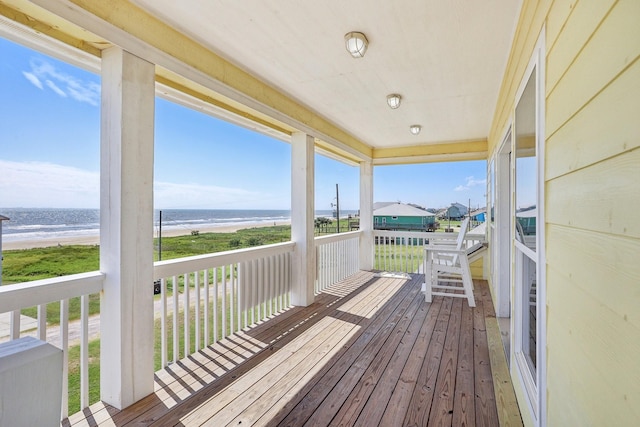 wooden terrace featuring a view of the beach and a water view