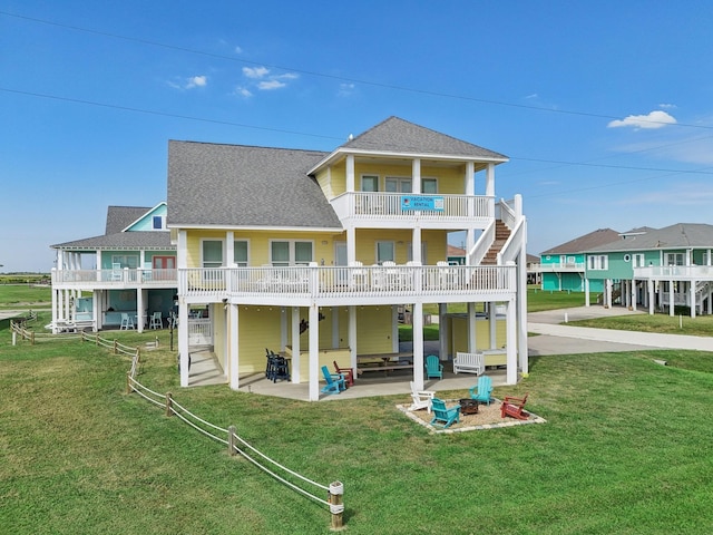 rear view of house with a yard, a patio area, and a shingled roof