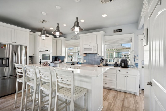 kitchen featuring white appliances, tasteful backsplash, white cabinets, and light countertops