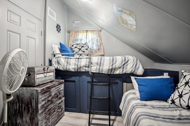 bedroom with visible vents, lofted ceiling, and wood finished floors