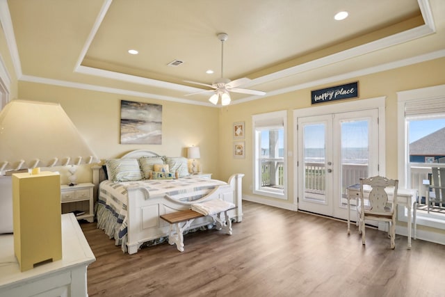 bedroom featuring a raised ceiling, crown molding, wood finished floors, and access to exterior