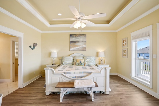 bedroom with baseboards, a raised ceiling, wood finished floors, and crown molding