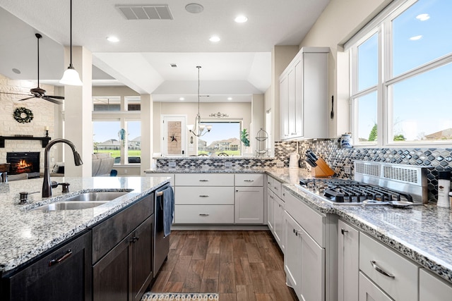 kitchen with light stone countertops, visible vents, a sink, a stone fireplace, and appliances with stainless steel finishes