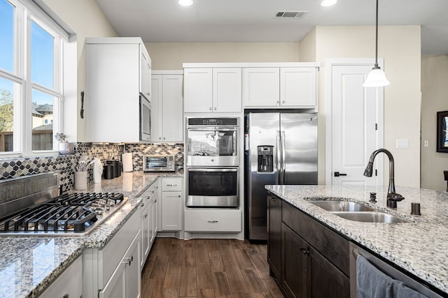 kitchen with a sink, visible vents, appliances with stainless steel finishes, and decorative backsplash