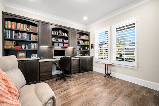 office space with light wood finished floors, built in study area, crown molding, and baseboards