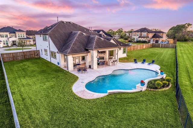 pool at dusk featuring a fenced in pool, a residential view, a lawn, a fenced backyard, and a patio