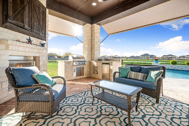 view of patio with fence, a fenced in pool, exterior kitchen, an outdoor living space with a fireplace, and grilling area