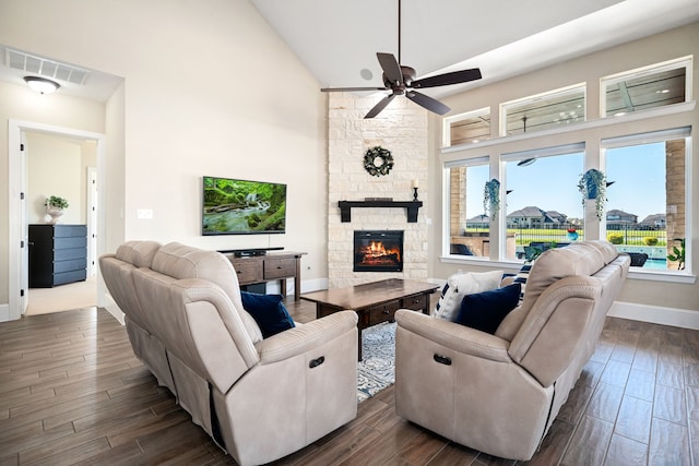 living room with visible vents, high vaulted ceiling, a stone fireplace, and dark wood-style floors