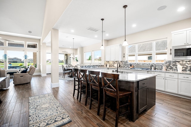 kitchen with visible vents, decorative backsplash, a sink, dark wood-style floors, and built in microwave