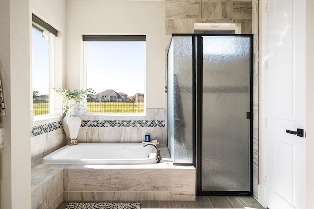 bathroom featuring a shower stall, a garden tub, and a wealth of natural light