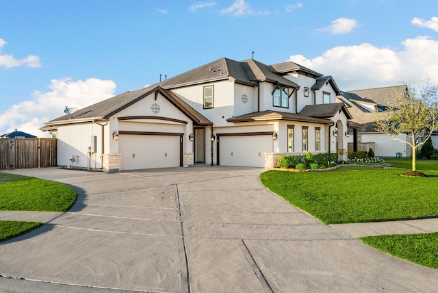 view of front of house with stucco siding, driveway, a front yard, and fence