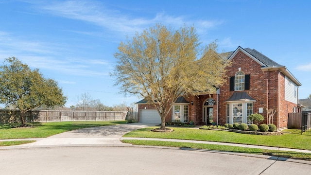 traditional-style house featuring driveway, a front lawn, fence, an attached garage, and brick siding