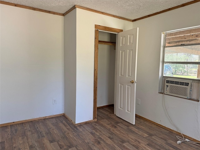 unfurnished bedroom featuring baseboards, ornamental molding, cooling unit, wood finished floors, and a textured ceiling